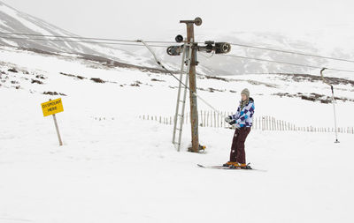 Woman walking on snow covered field against sky