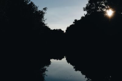 Silhouette trees by lake against sky during sunset