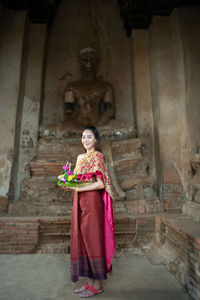 Young woman wearing traditional clothing looking away while standing outside building