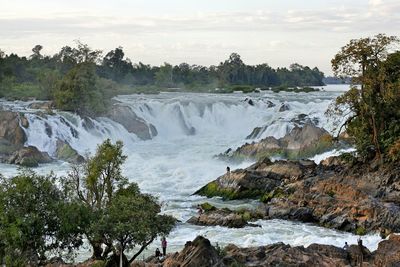 Scenic view of waterfall by sea against sky