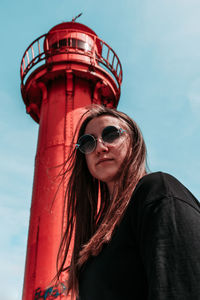 Low angle view of woman wearing sunglasses while standing against tower