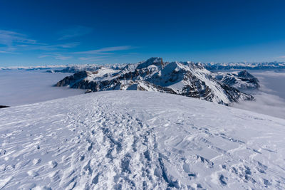 Aerial view of snowcapped mountains against blue sky