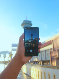 Close-up of hand holding smart phone against clear sky