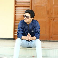 Young man sitting against wall