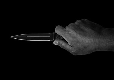 Close-up of hand holding glass against black background