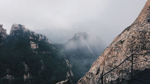 Low angle view of mountain against sky during foggy weather