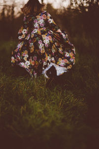 Rear view of woman running on grass during sunset
