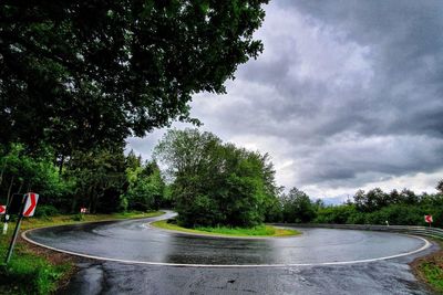 Empty road amidst trees against sky