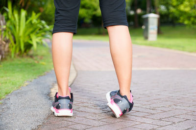 Low section of woman standing on footpath