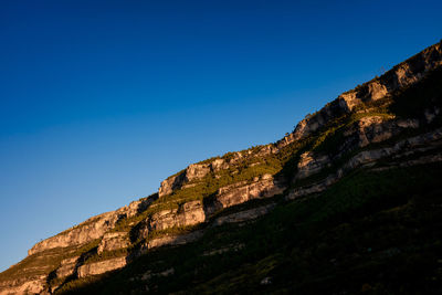 Low angle view of mountain against clear blue sky