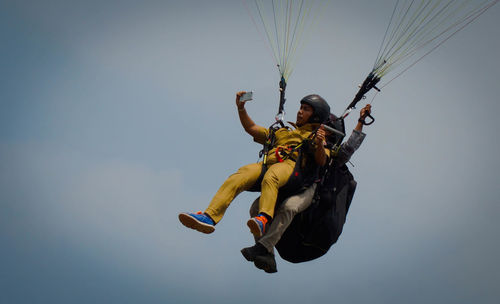 Low angle view of man paragliding against sky