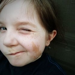 Close-up portrait of girl with freckles on face winking indoor