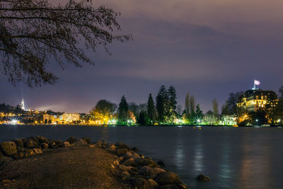 River by illuminated city against sky at night