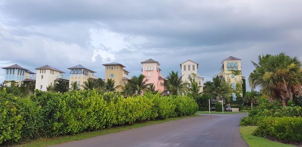 Road amidst plants and buildings against sky