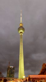 Low angle view of communications tower in city against sky