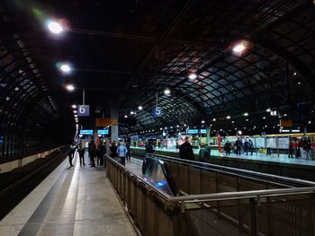 People waiting at railroad station platform at night