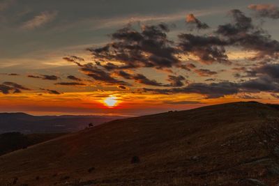 Scenic view of landscape against dramatic sky during sunset