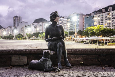 Man with dog sitting against buildings in city