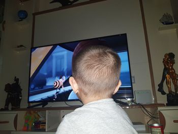 Rear view of boy looking at camera at home