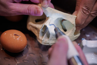 Cropped hand of woman holding dentures