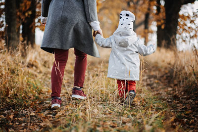 Mother and little baby daughter walking together in autumn park, forest. mother with toddler