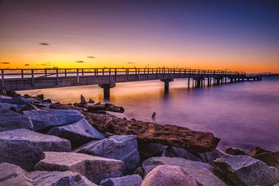 Pier over sea against sky during sunset