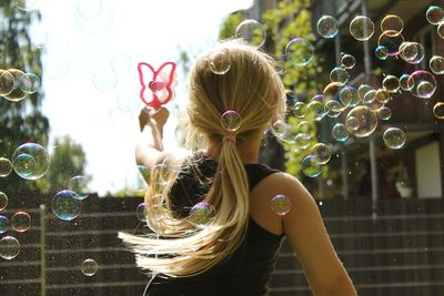Rear view of girl blowing bubbles outdoors