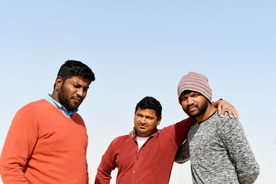 Friends looking at camera against clear sky