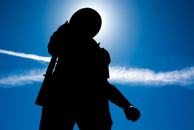 Low angle view of silhouette people standing against blue sky