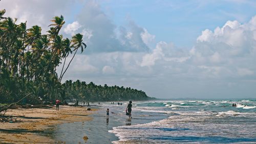 People at beach against cloudy sky