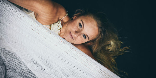 Portrait of woman with textile against black background