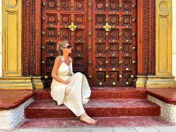 Portrait of woman sitting against closed doors