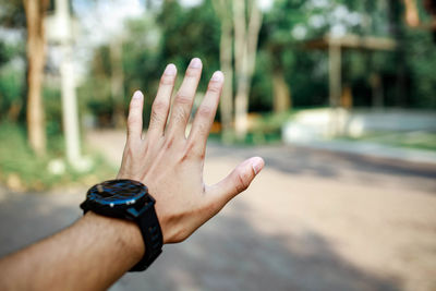 Cropped image of hand with wristwatch against blurred background