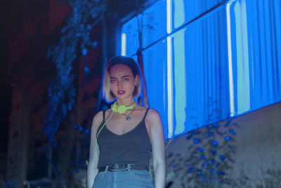 Portrait of smiling young woman standing against blue wall