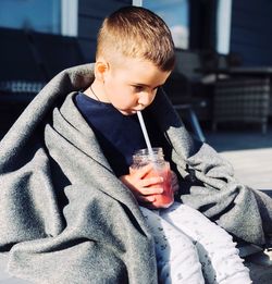 Cute boy drinking smoothie in city