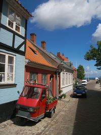 Cars on road by buildings against sky