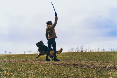 Man with dog on field against sky