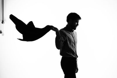 Side view of young man standing against white background