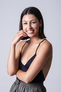 Beautiful young girl posing and smiling in a studio with a grey