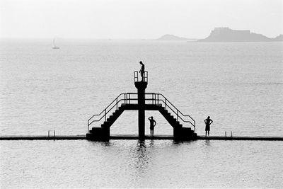 People standing by sea against clear sky