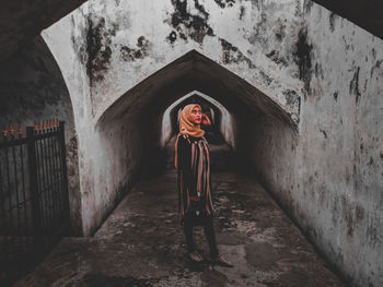 Full length portrait of woman standing against building