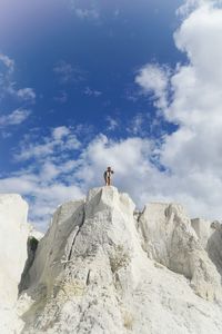 Low angle view of woman on white rock formation against sky