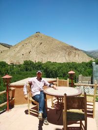 Man sitting at outdoor restaurant against mountain