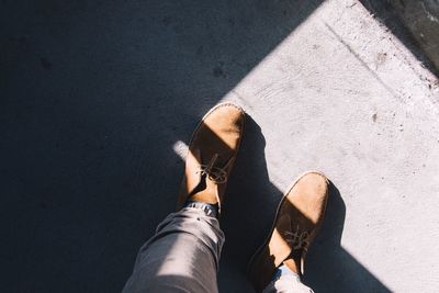 Low section of man standing outdoors during sunny day