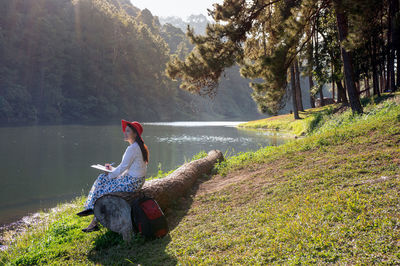 Man sitting by lake against mountain