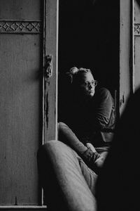 Man smoking while sitting on door