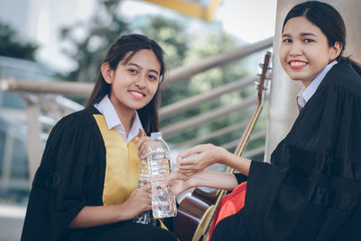 Portrait of smiling friends in graduation gown