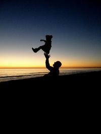 Silhouette of people on beach at sunset