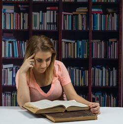 Young woman reading book while sitting at library