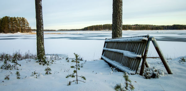 Scenic view of snow covered field by lake against sky